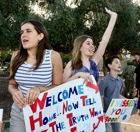 The family of returning sailor Will Robesky waves as he is spotted leaving the bus on Sunday. 